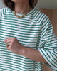 T-shirt w zielone paski widoczny z profilu, stylizowany na codzienny look z nutą elegancji.