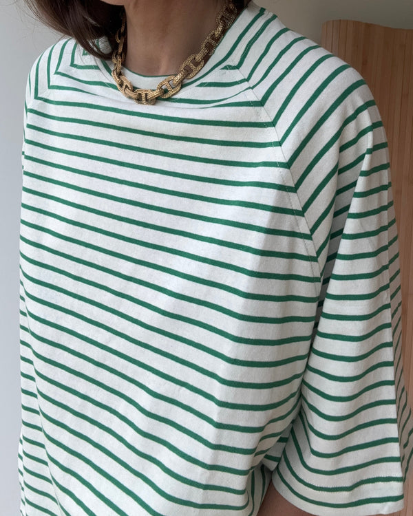 Zbliżenie na detal t-shirta w zielone paski – luźny krój i miękka bawełna.