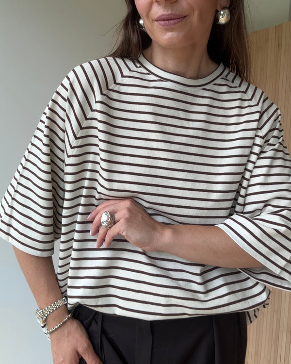 Zbliżenie na dekolt i rękaw t-shirta w czekoladowe paski z miękkiej bawełny.